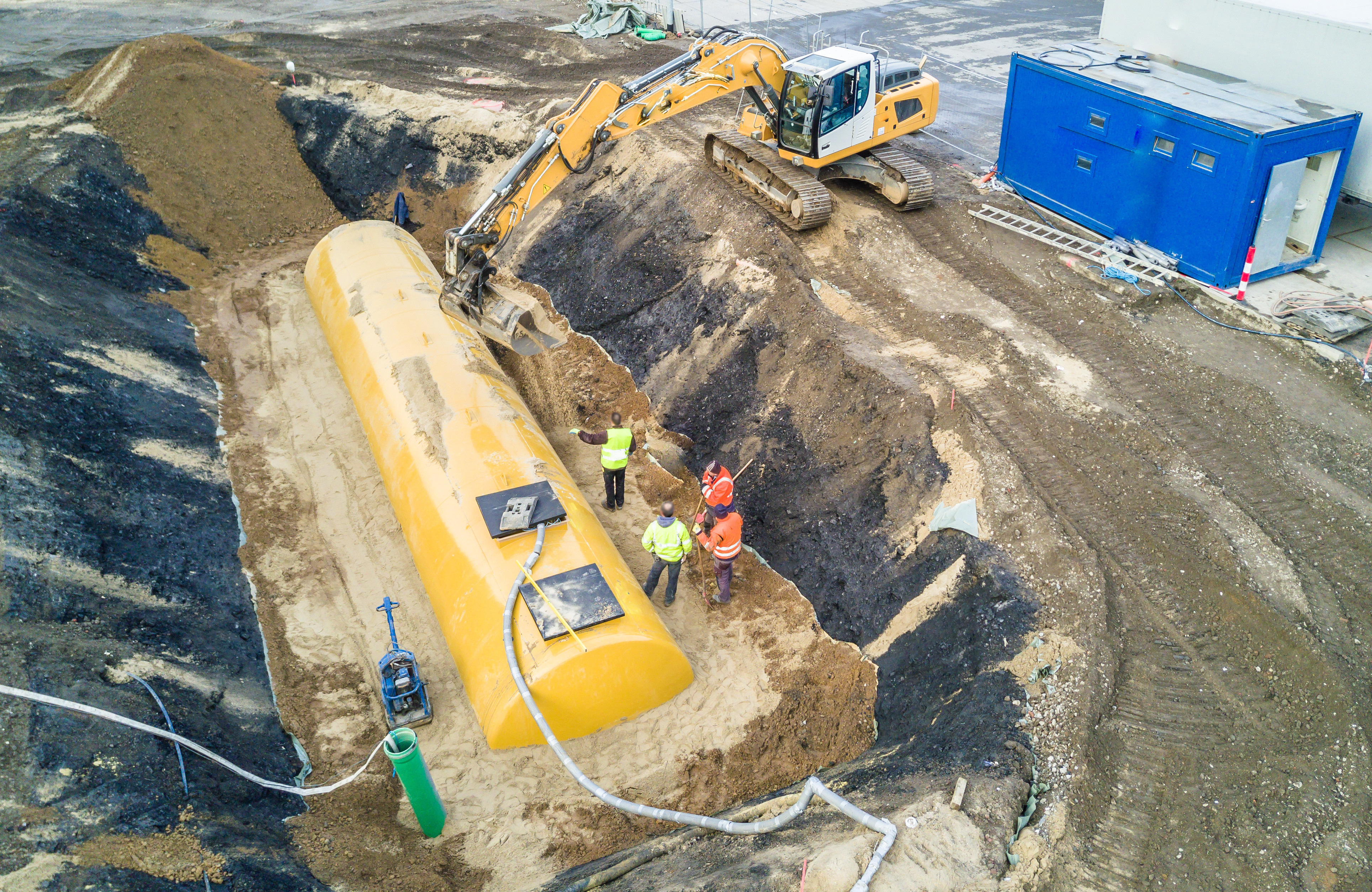 Worker installing a huge underground fuel tank, aerial